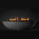 Oval fire pit bowl with burning flames and black lava rocks, concrete-gray finish