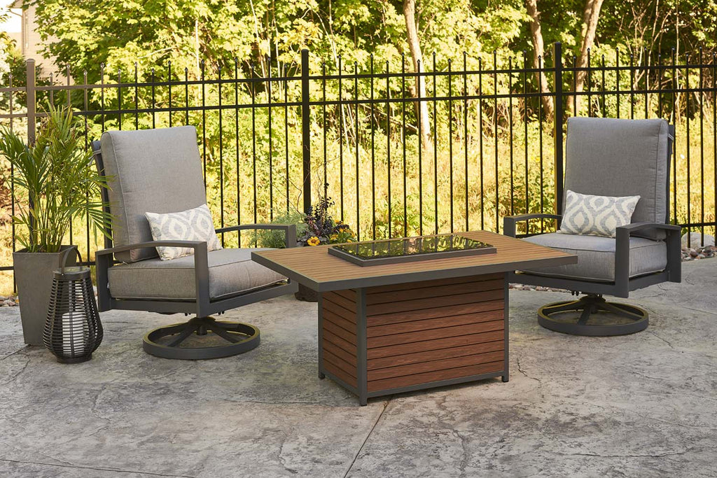 Outdoor gas fire pit table with visible flames and two matching lounge chairs