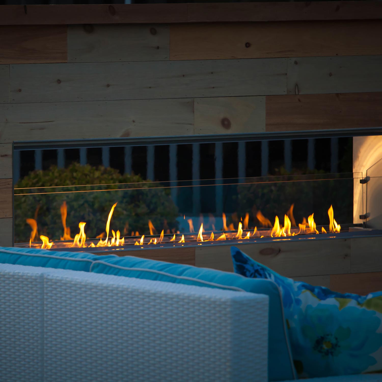 Outdoor fireplace burner with visible flames inside open firebox