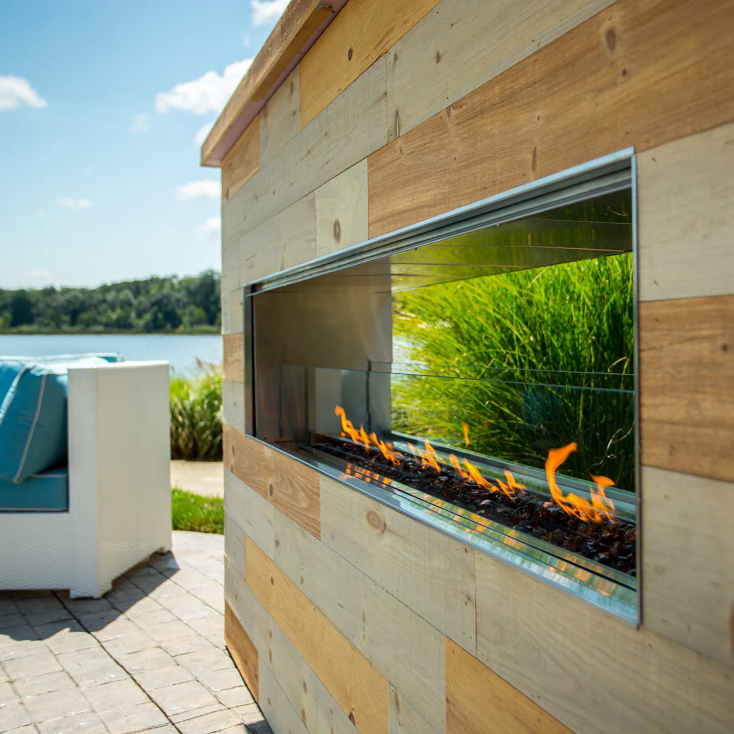 Outdoor linear see-through gas fireplace with glass front and visible flames