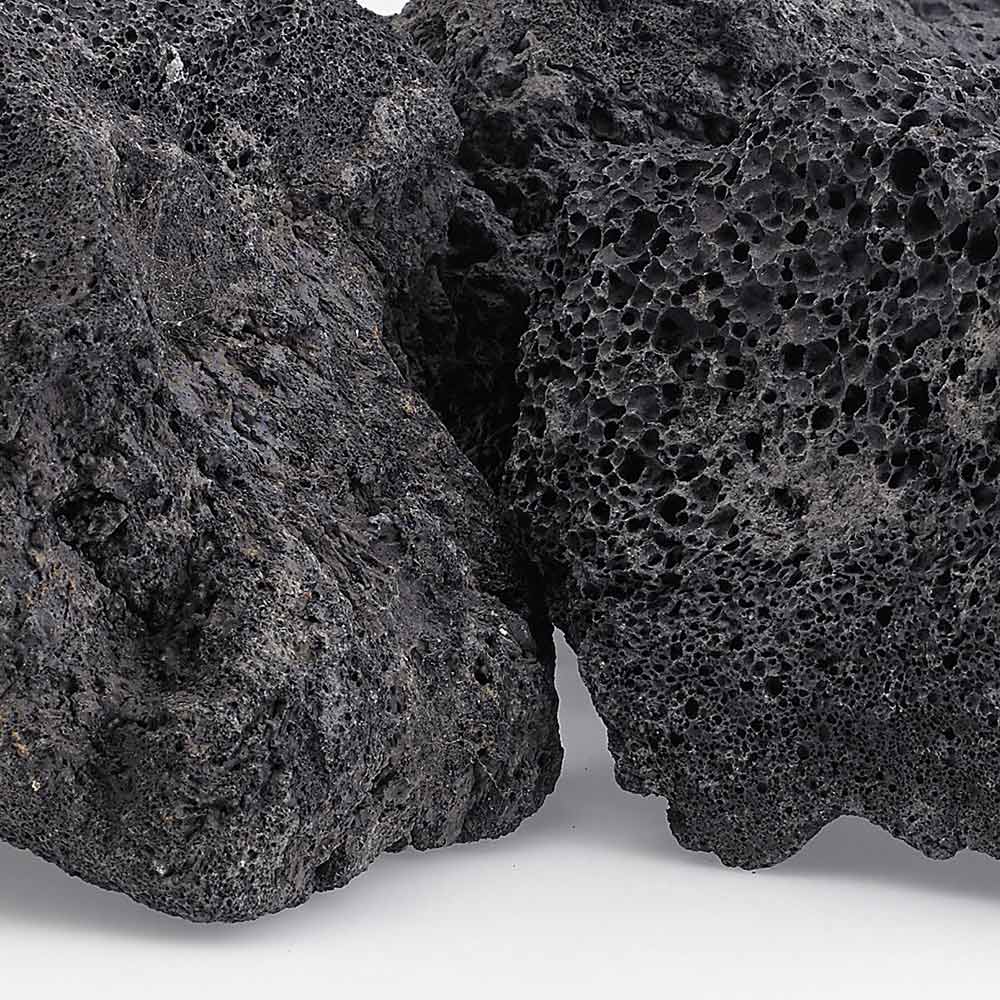 Close-up of black lava rock with dense porous texture and pitted surface