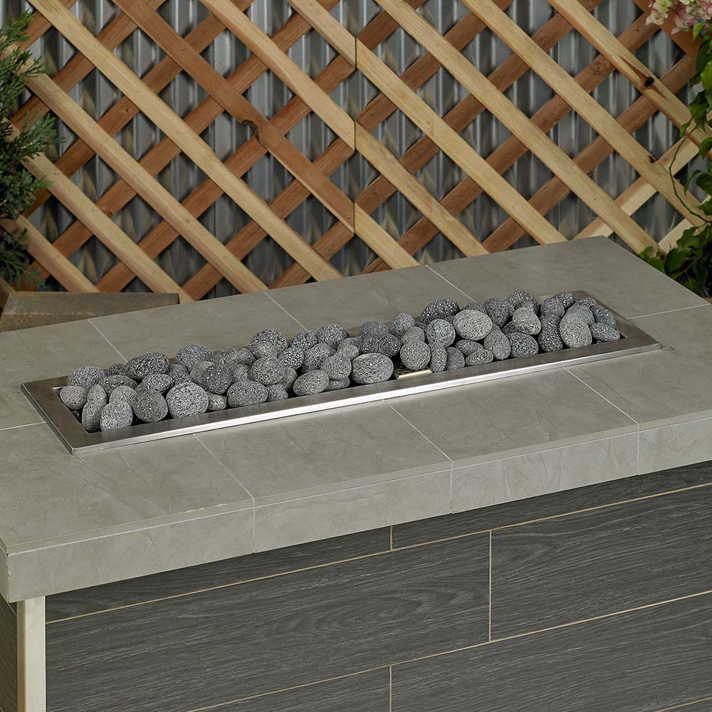 Rectangular tray of gray lava stones on outdoor fire pit surround