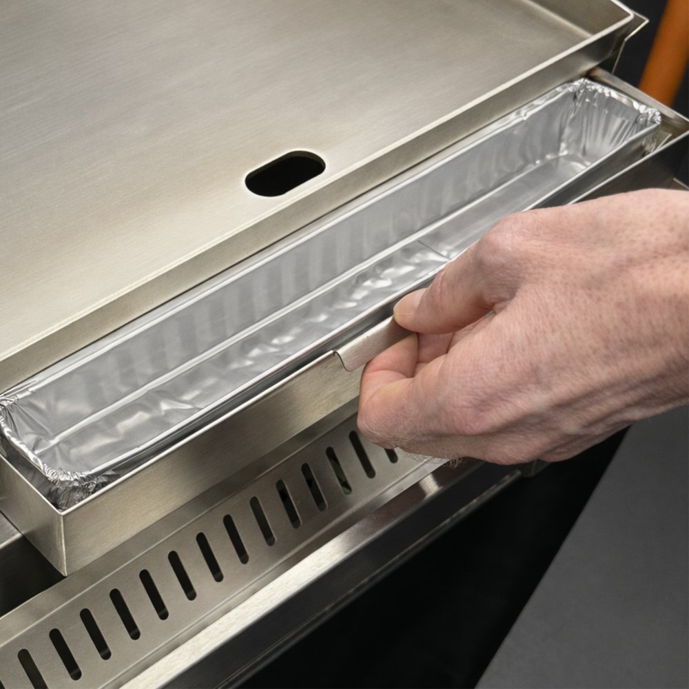 Disposable aluminum grease tray liner placed in a grill grease tray