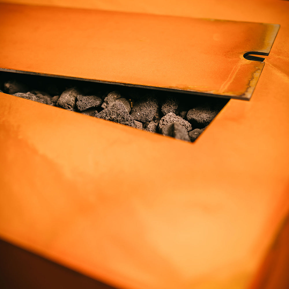 Rectangular gas fire pit burner showing lava rocks under cover