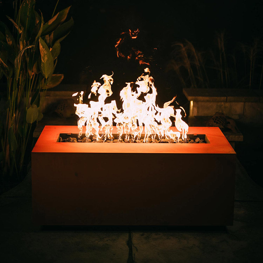 Linear gas fire pit with high orange flames over lava rocks