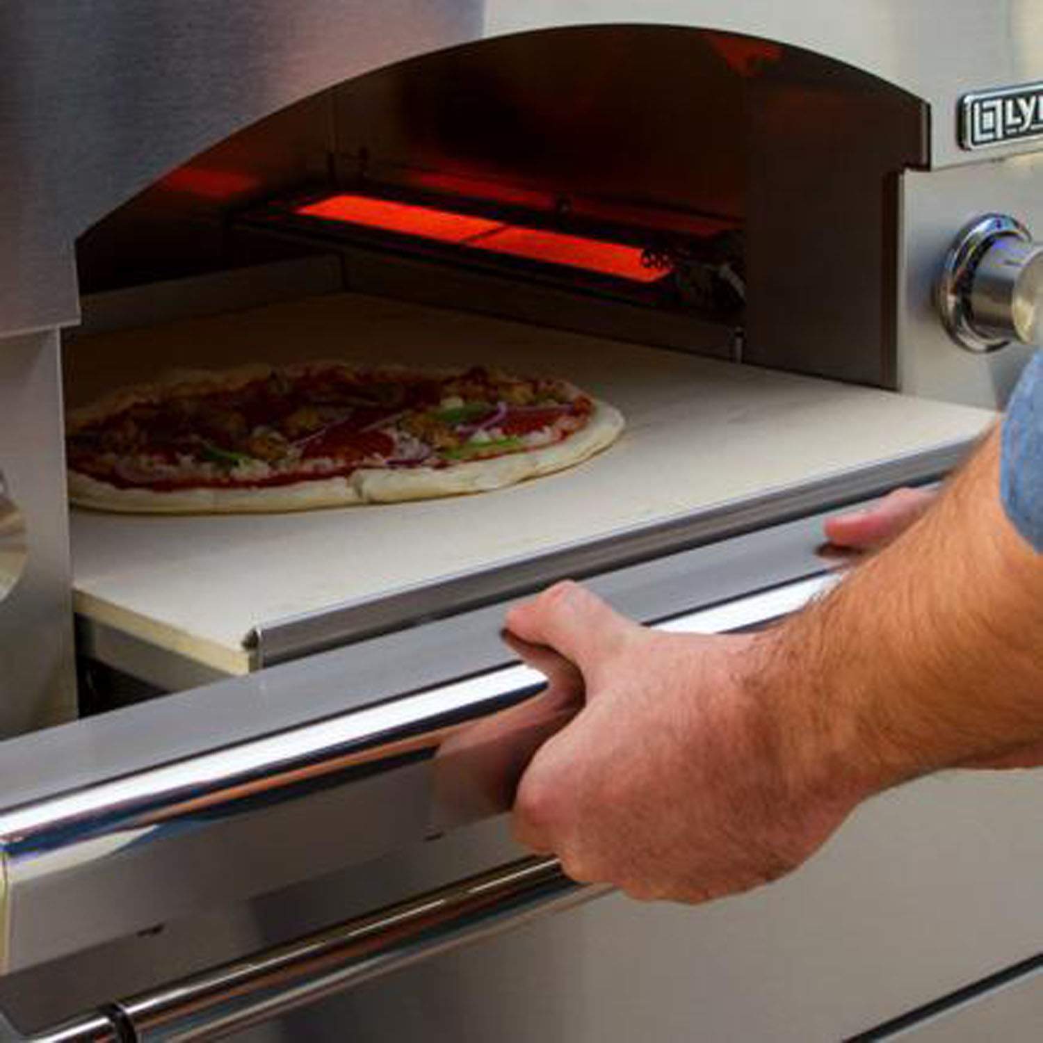 Hand sliding pizza oven drawer beside open baking chamber with pizza