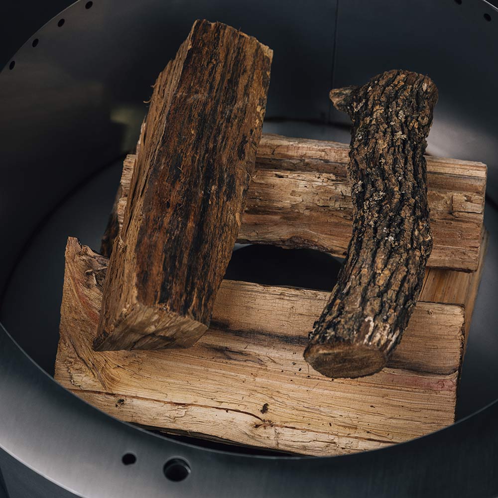 Wood fire pit interior with stacked logs on a metal grate