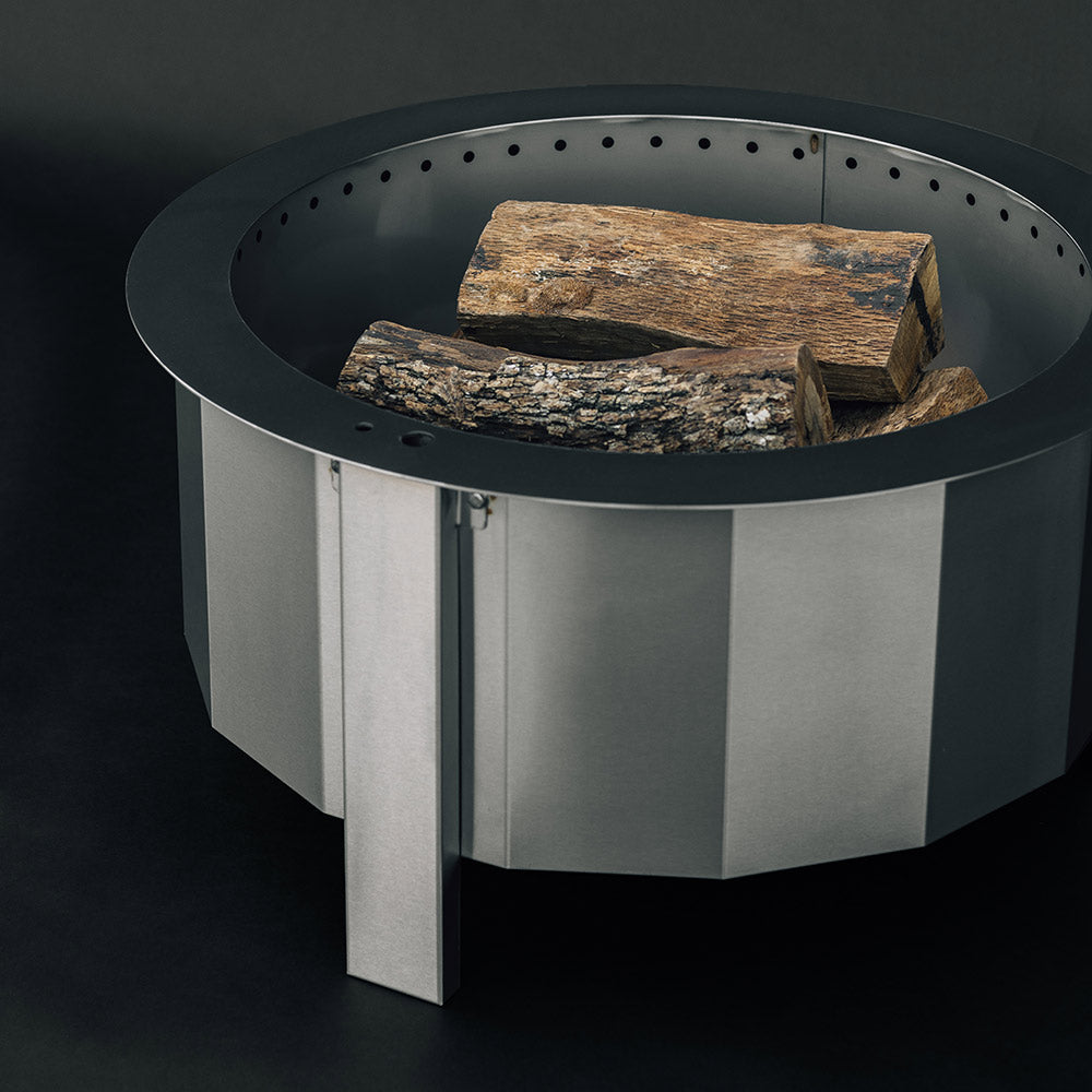 Metal fire pit with circular top ring and logs inside the burn bowl