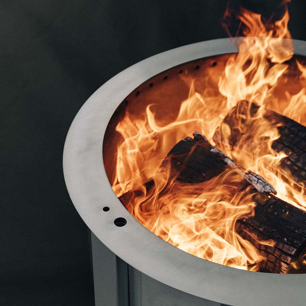 Wood fire pit with active flames burning inside the round metal bowl