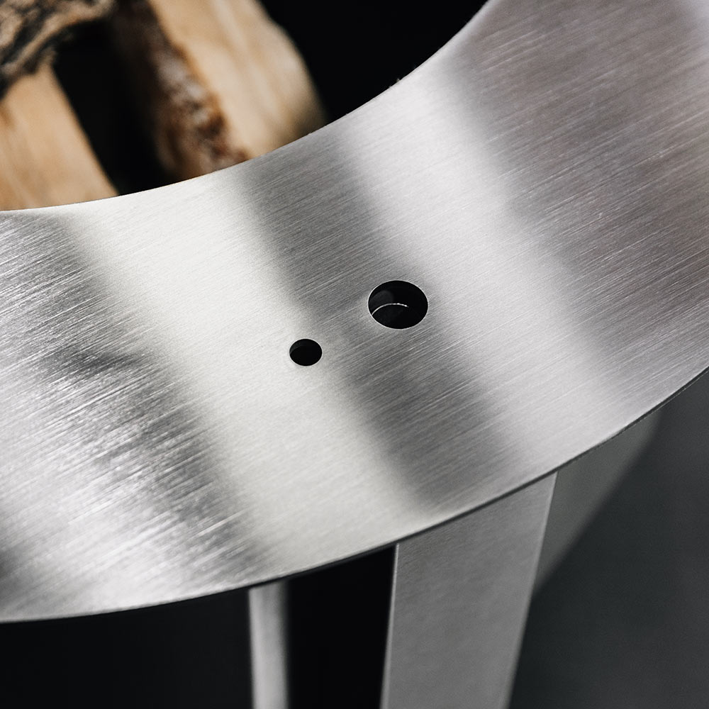 Close-up of steel fire pit bowl rim with two round vent holes
