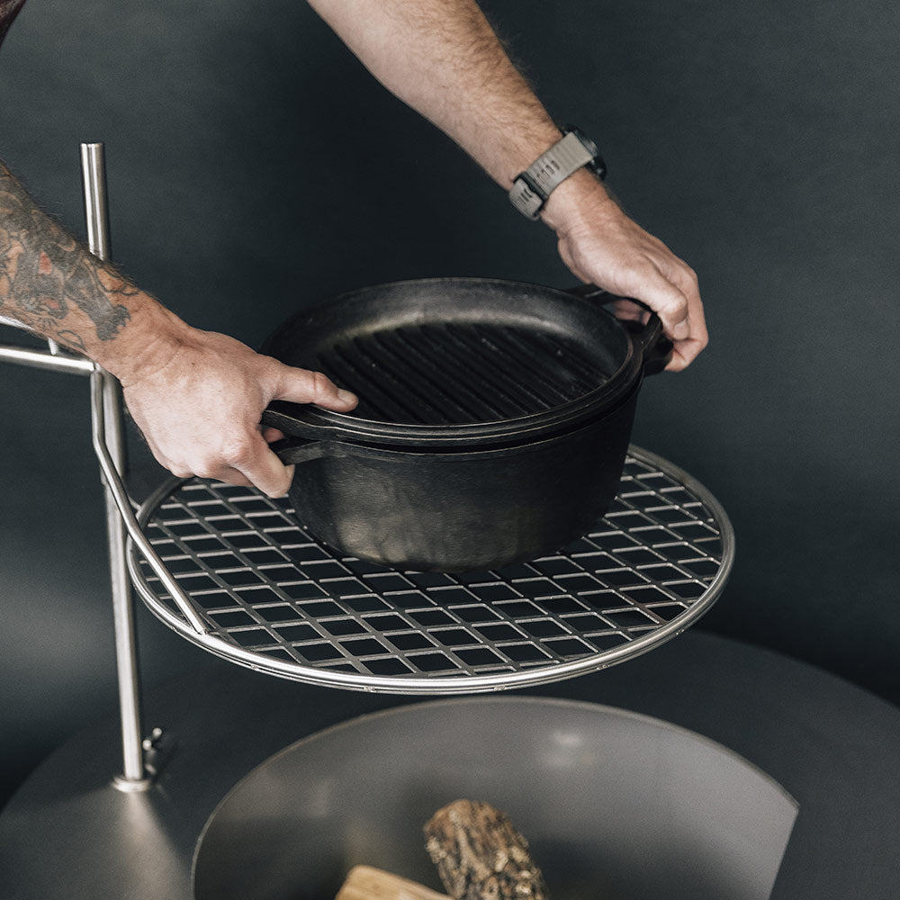Wire cooking grate holding a black pot on a round stand