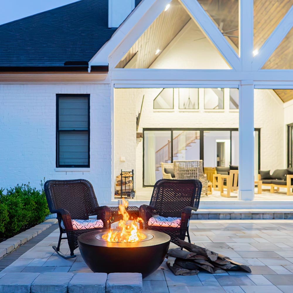 Dark GFRC wood fire bowl with flames burning in the center and stainless insert opening
