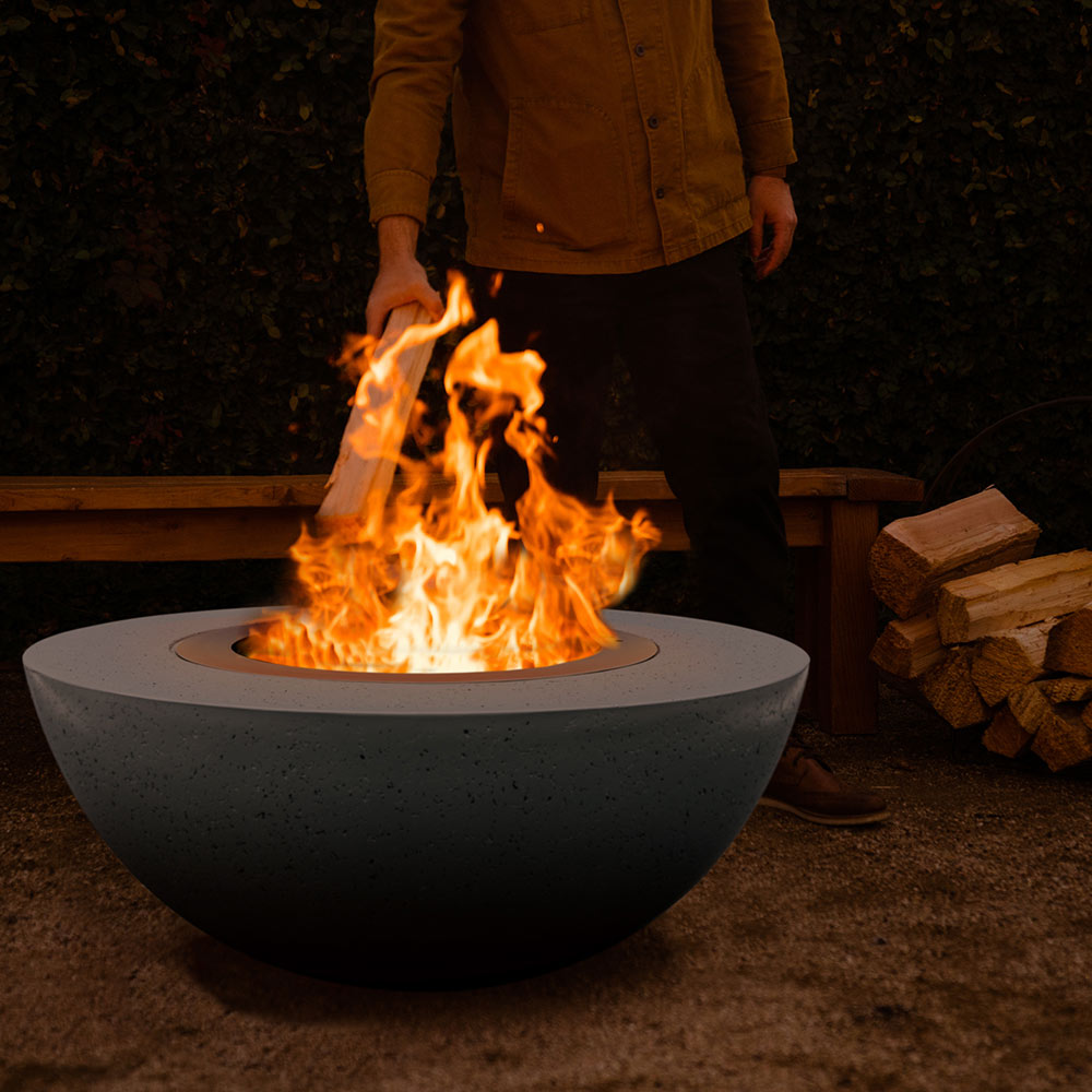 Flames in a smokeless stainless insert inside a dark GFRC wood fire bowl