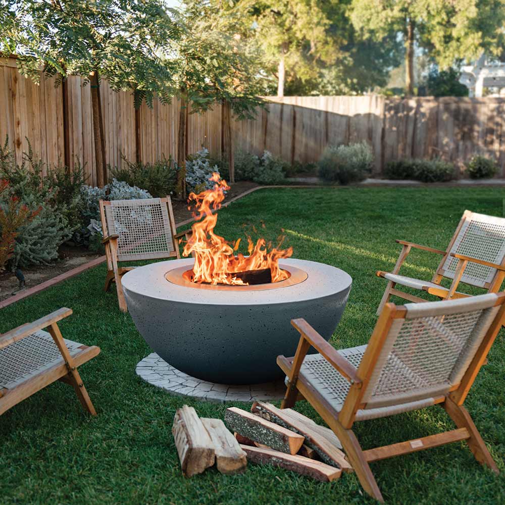 Dark speckled concrete fire bowl with stainless steel insert, burning wood flames visible