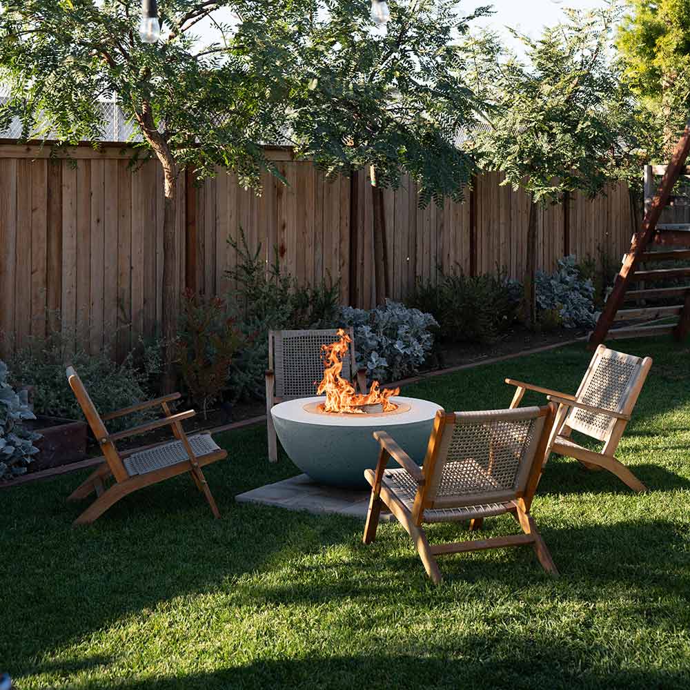 Dark speckled concrete fire bowl with stainless steel insert, flames in outdoor yard
