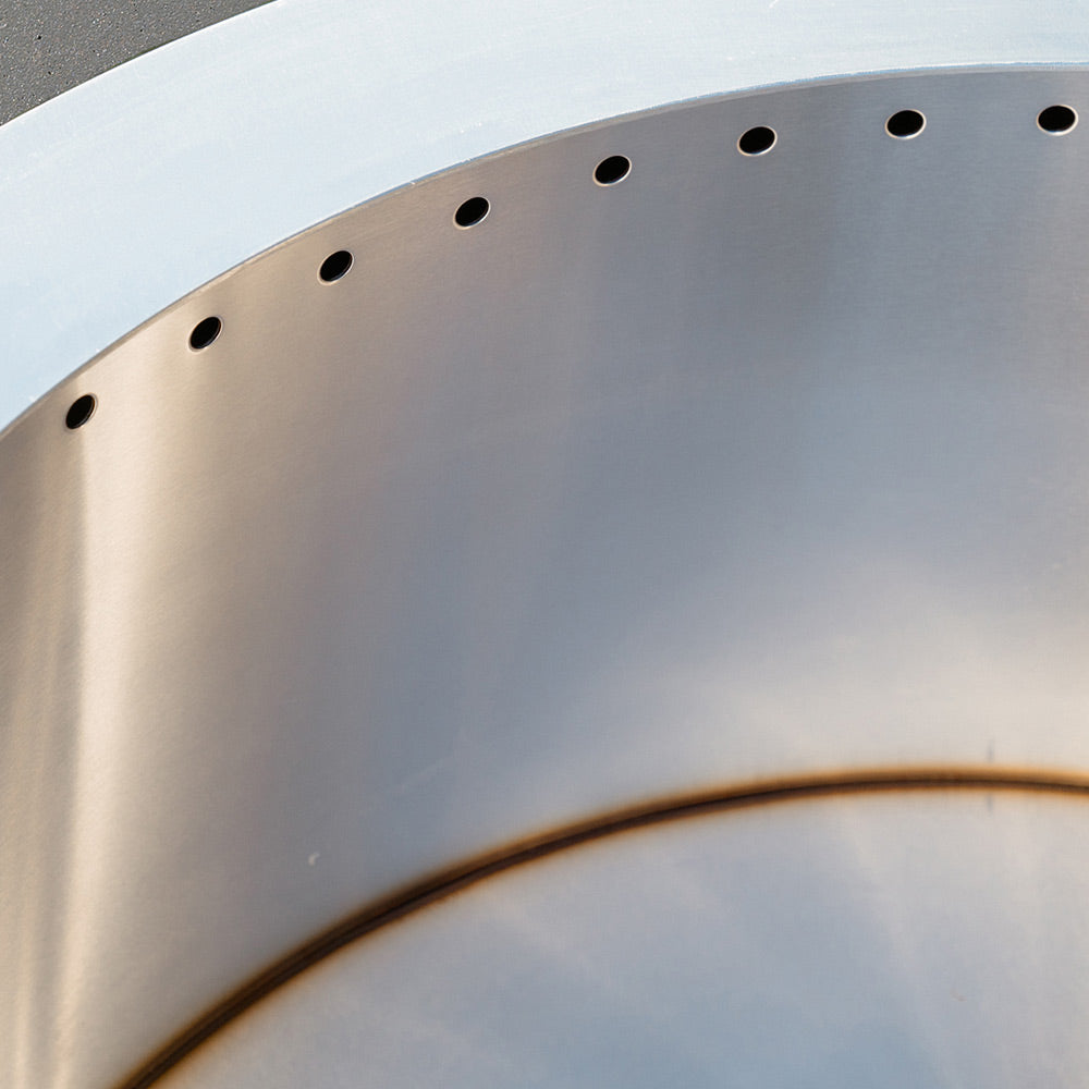 Smokeless stainless steel insert with vent holes inside dark GFRC fire bowl