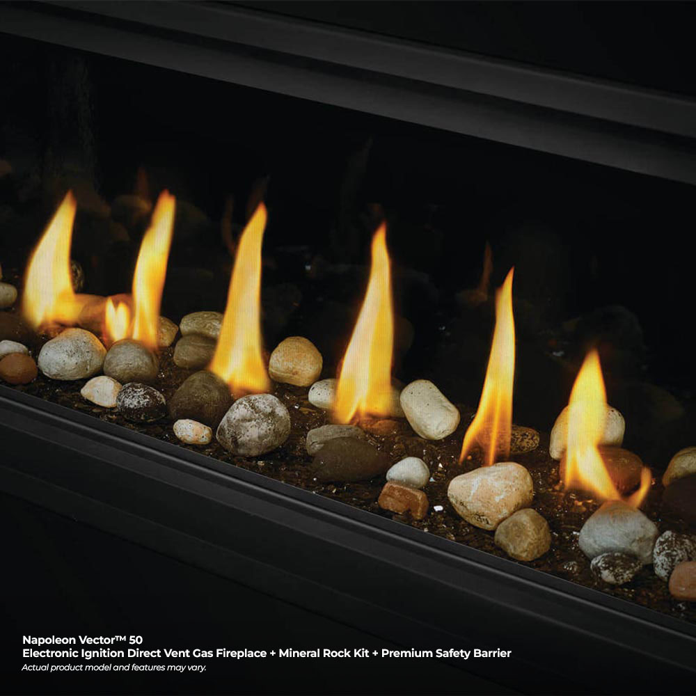 Direct vent gas fireplace flames burning over mixed mineral rocks in the firebox.