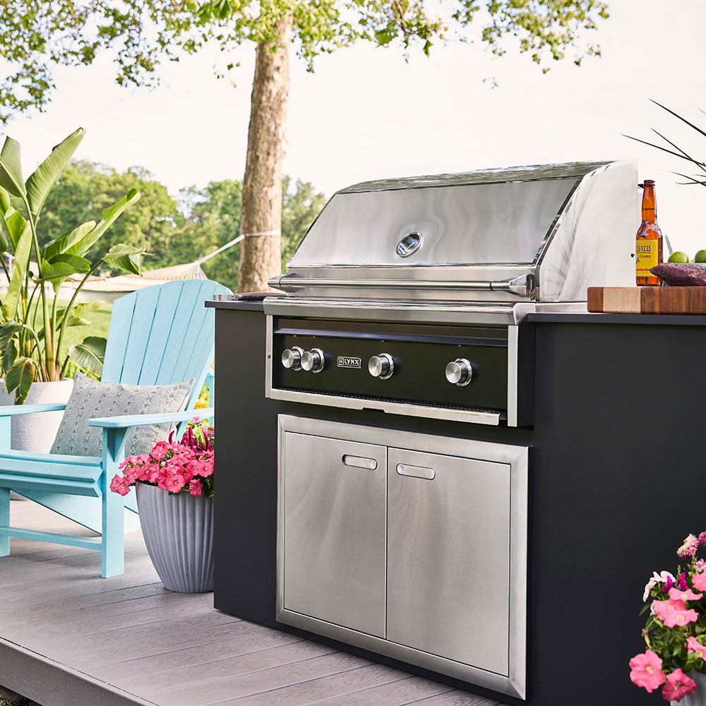 Built-in gas grill with open hood, three control knobs, and cabinet doors