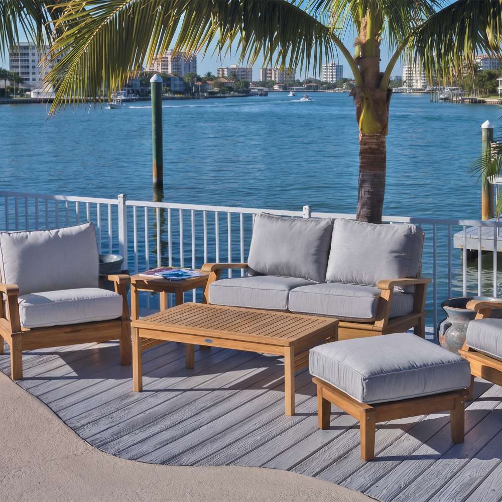 Outdoor seating arrangement featuring an ottoman with light gray cushion and wood frame