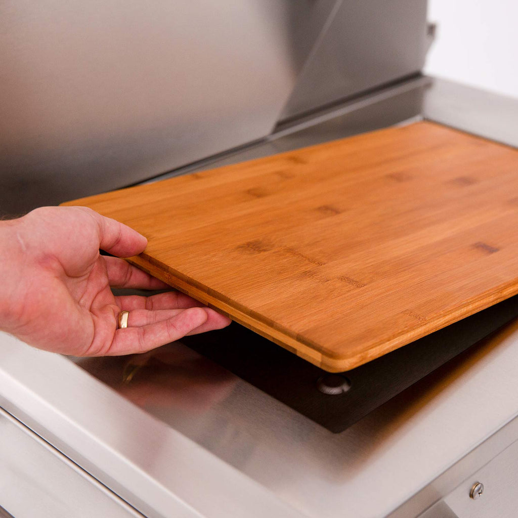 Wood side shelf attachment on a stainless grill cart with rounded front corner.