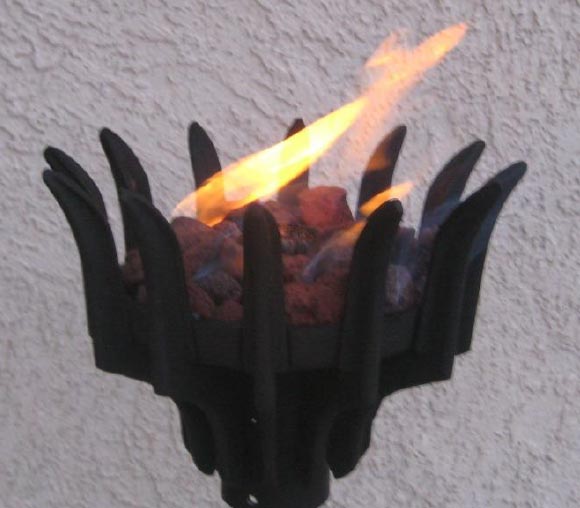 Gas torch head with orange flame rising from black pronged burner