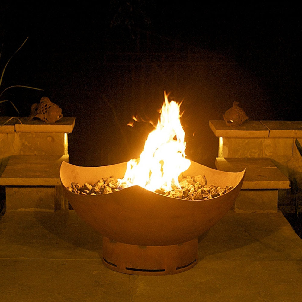 Bronze manta ray gas fire pit burning with visible flame and stone fire bed