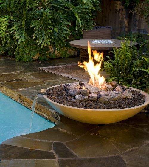 Round GFRC gas fire and water bowl with visible flame and pebble-style fire bed