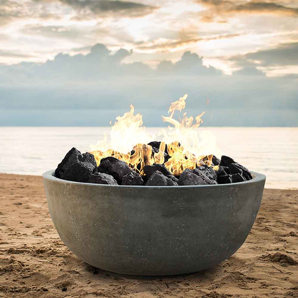 Concrete gas fire pit bowl in gray with burning flames and dark fire rocks