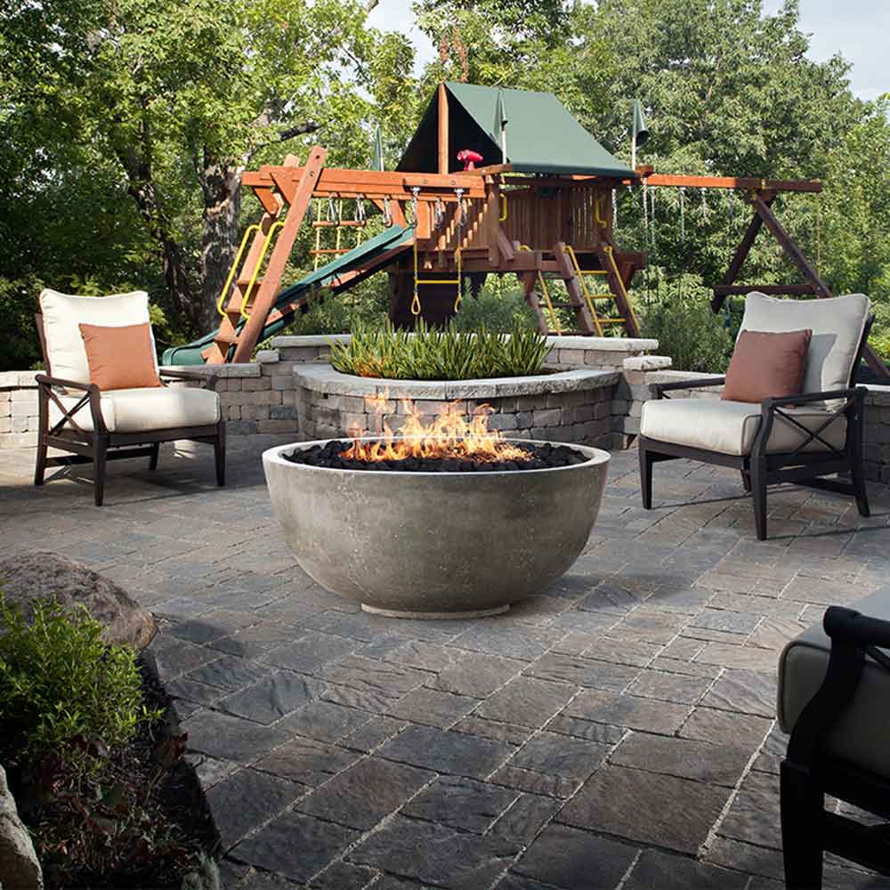 Concrete gas fire pit bowl in gray with visible flames, round outdoor design
