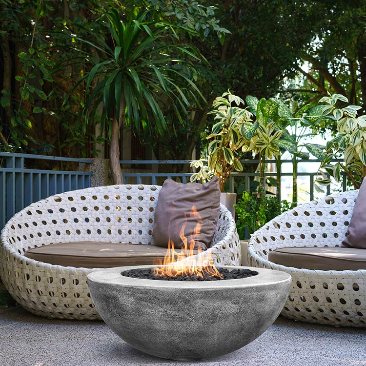 Concrete gas fire pit with visible flames in a backyard patio setting
