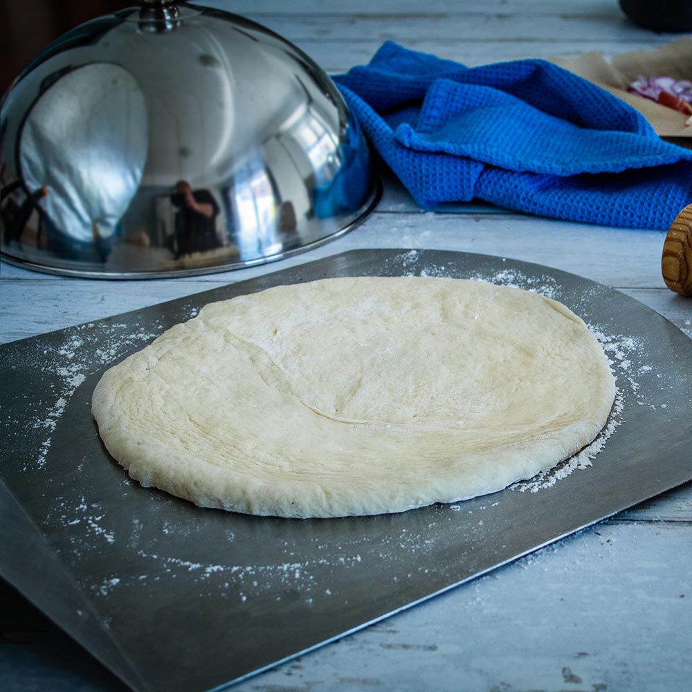 Stainless steel cooking dome with knob over flat dough