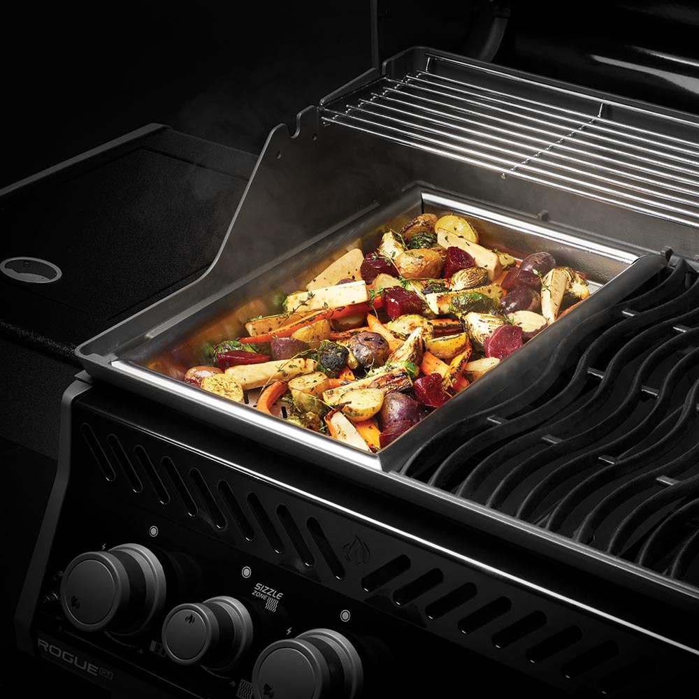 Napoleon cast iron frying pan filled with roasted vegetables on a grill