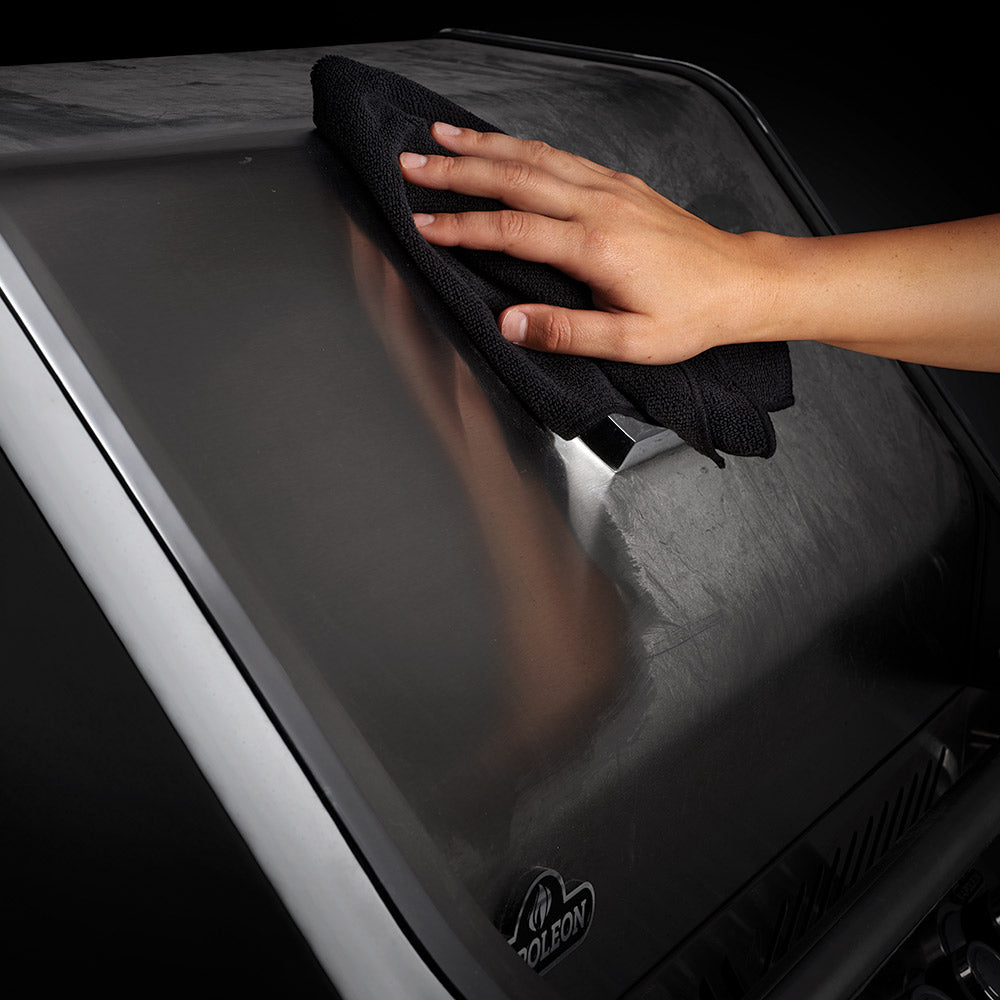 Microfiber cleaning towel wiping a car surface with a hand, dark gray