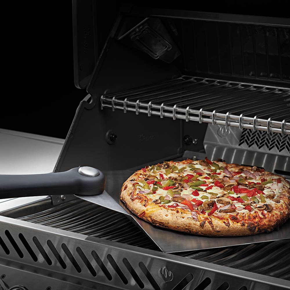 Napoleon PRO pizza spatula lifting pizza on a grill grate