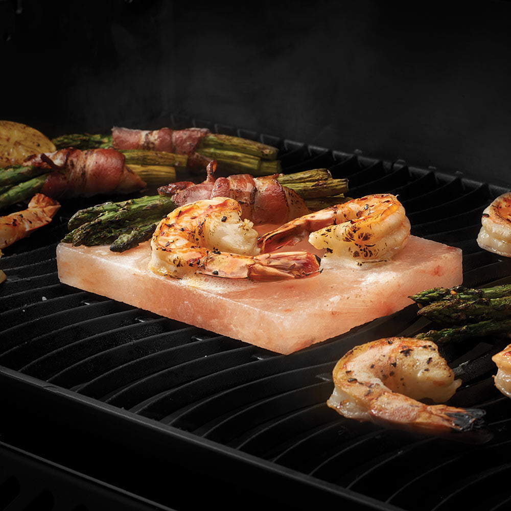 Salt stone slab on grill with seafood and vegetables on top