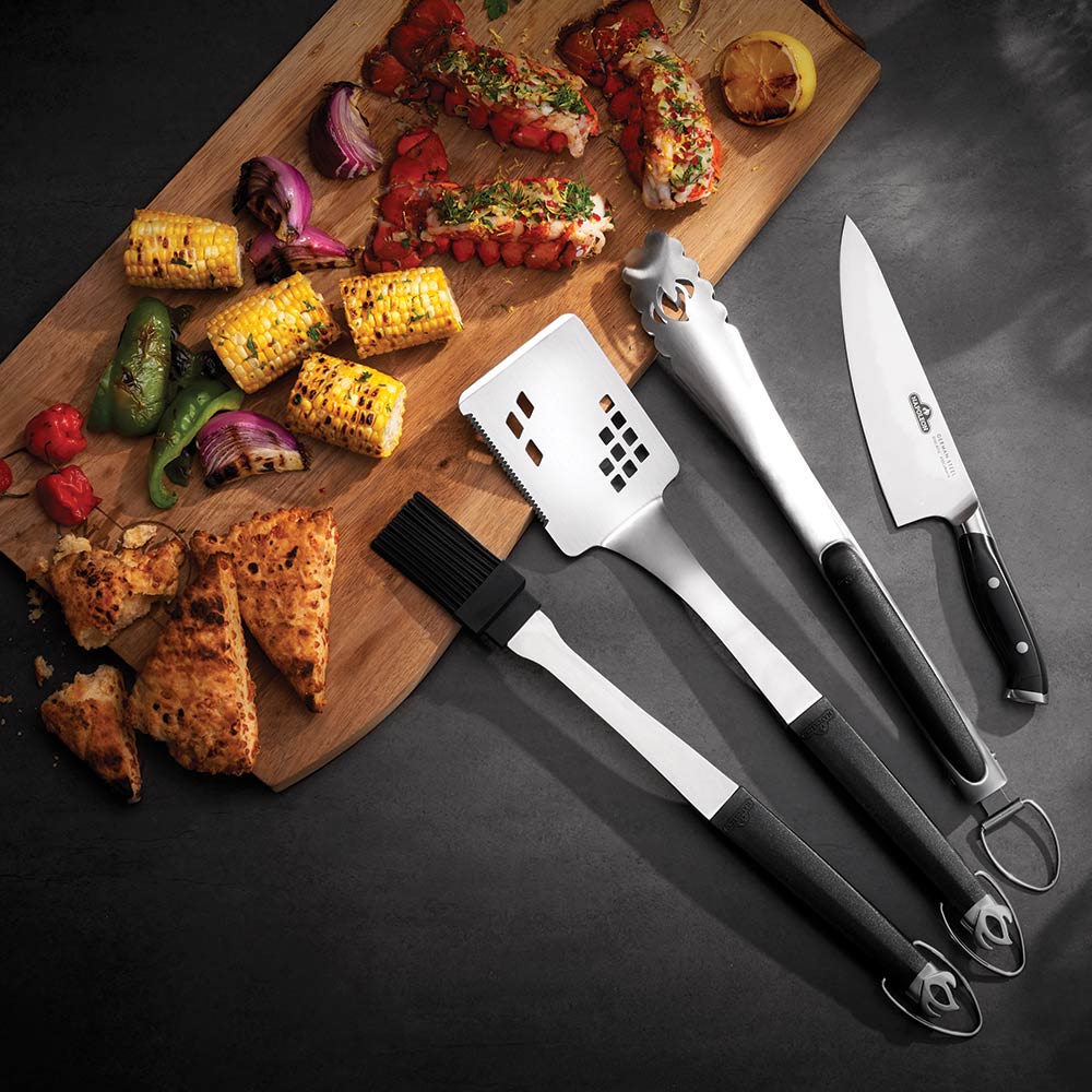 4-piece BBQ utensil set with black handles and stainless blades on prep board