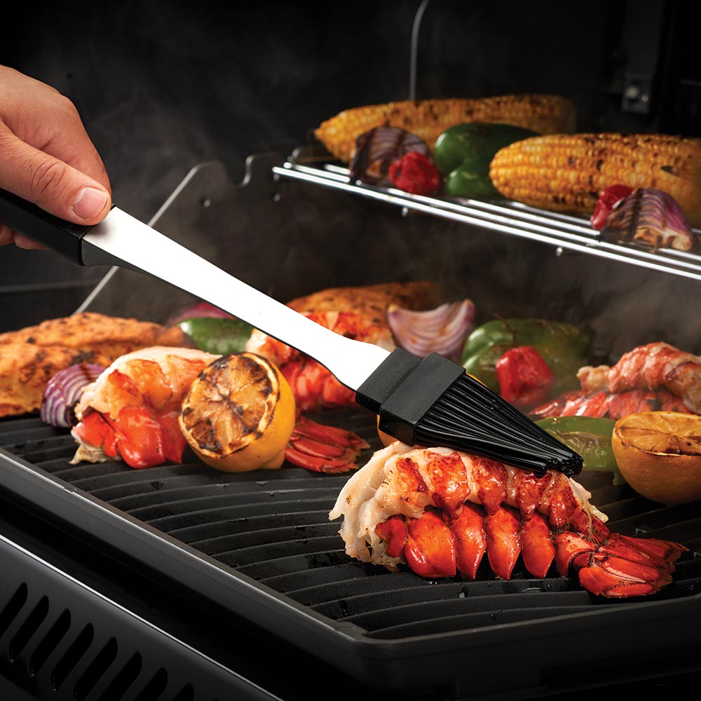 BBQ spatula with black grip lifting grilled food on metal grill