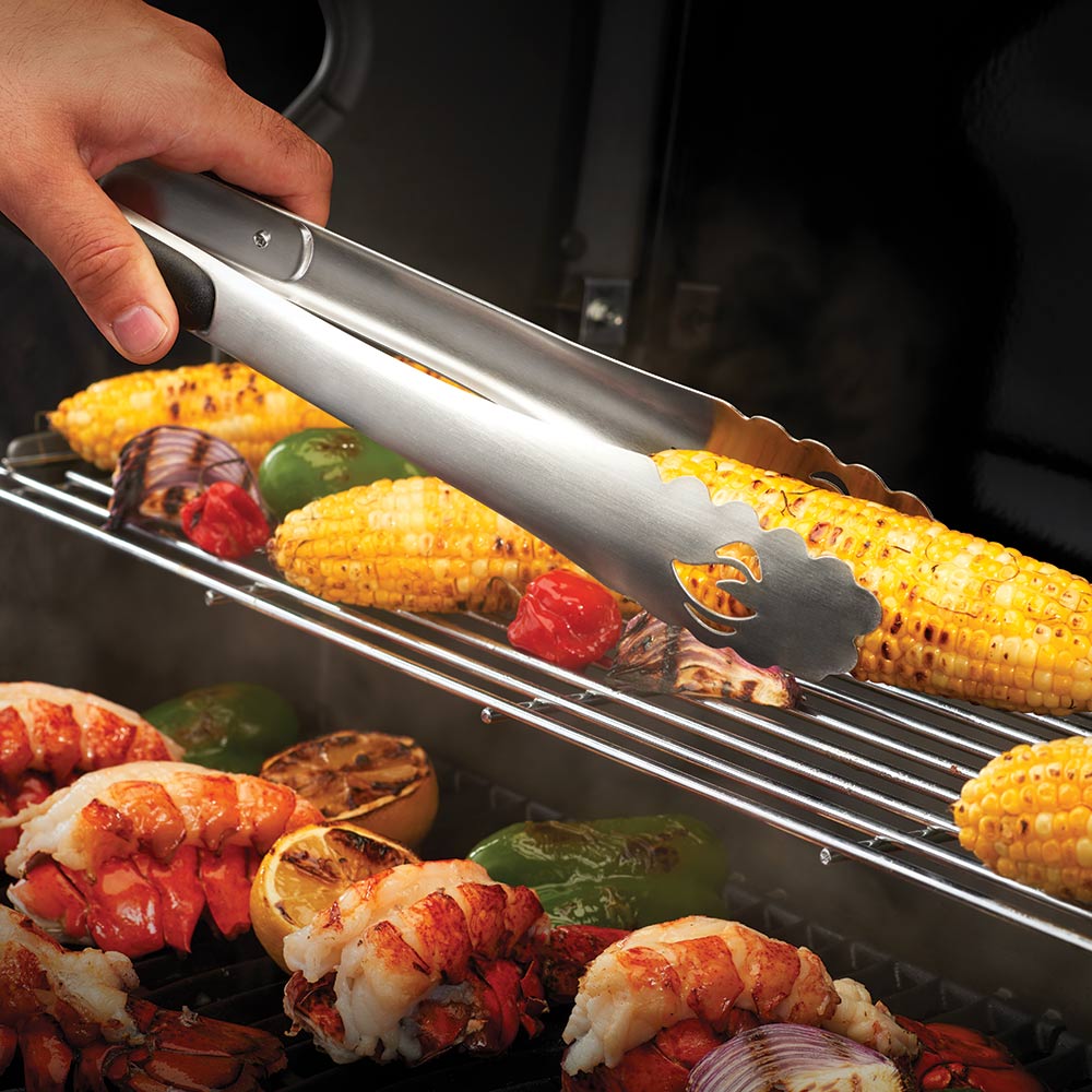 BBQ tongs with black grip holding corn and seafood on grill