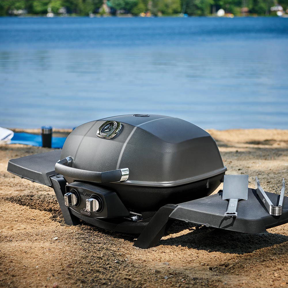 Black side shelf attached to portable grill for outdoor cooking