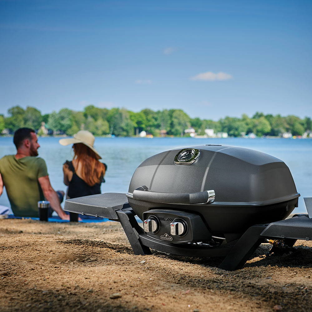 Black side shelf mounted on portable grill with control side visible