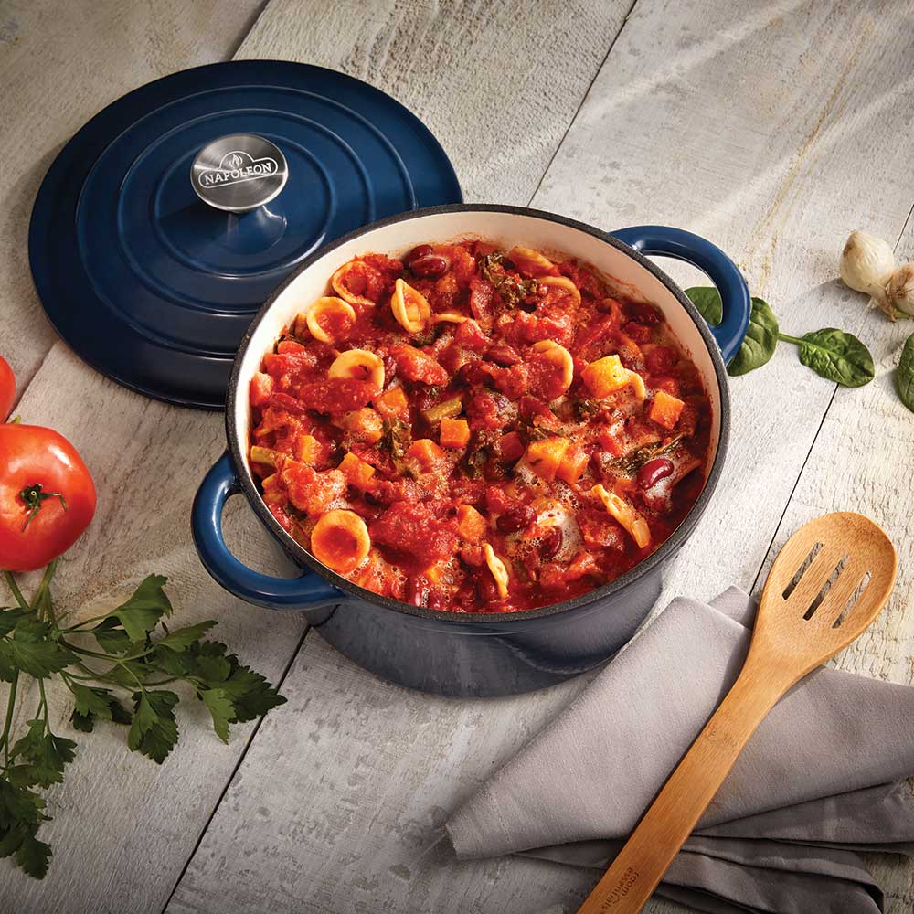 Blue cast iron casserole dish with lid set aside, filled with pasta in tomato sauce