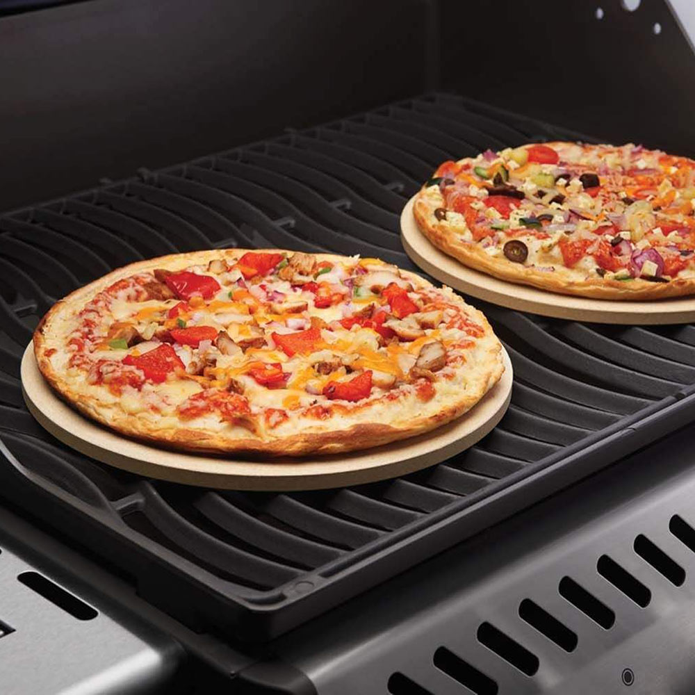 Round pizza stone on gas grill with topped pizza