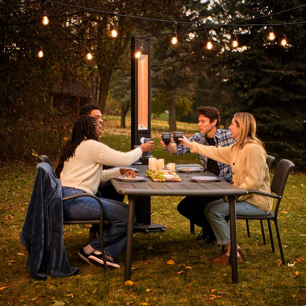 Outdoor electric infrared heater lit above patio table at night
