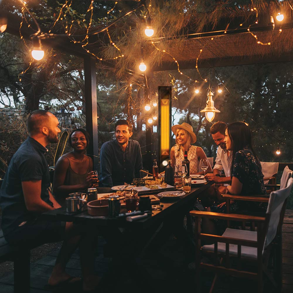 Freestanding outdoor electric infrared heater glowing near outdoor dining table