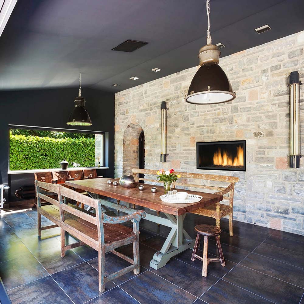 Built-in gas fireplace with glass firebox and burning flames in a stone surround