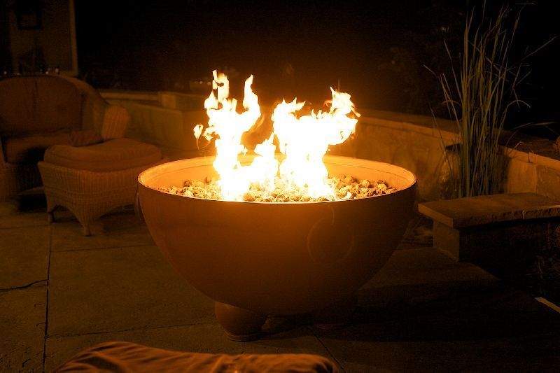 Gas fire pit bowl with burning flames in a round center