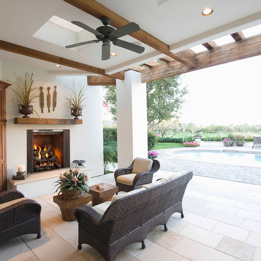 Outdoor wood fireplace inset in patio wall with burning firebox and wood mantel