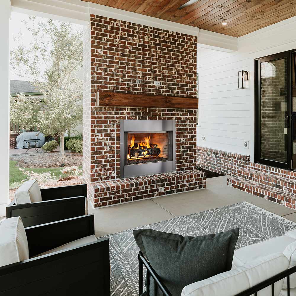 Outdoor wood-burning fireplace set in red brick and stone surround, visible flames