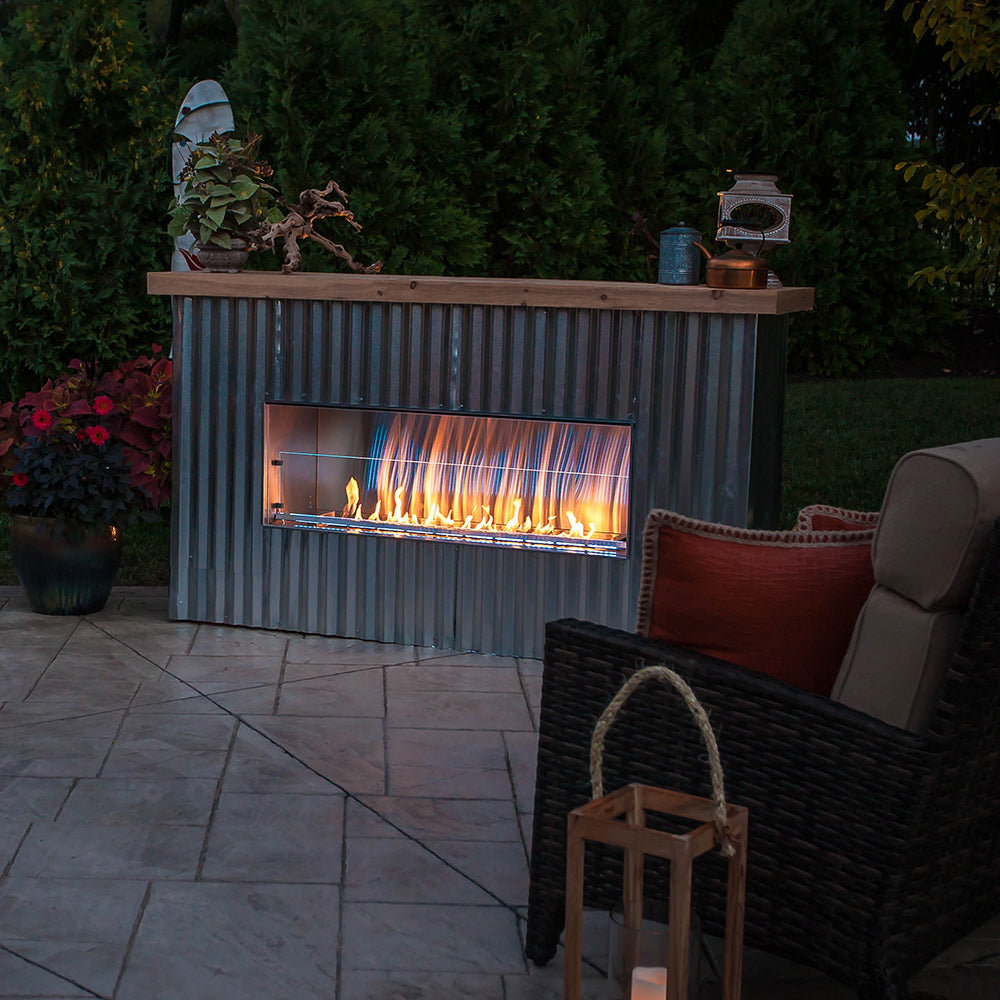 Outdoor linear fireplace in gray cabinet with glass front and orange flames.