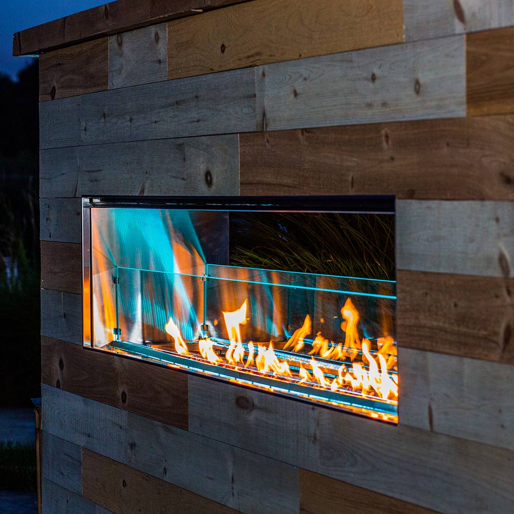 Linear outdoor fireplace firebox with glass and blue-and-orange flame LED light